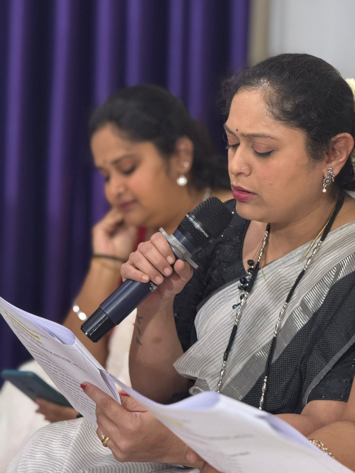 Mayuri Apte Jejurikar reading from a script with microphone
